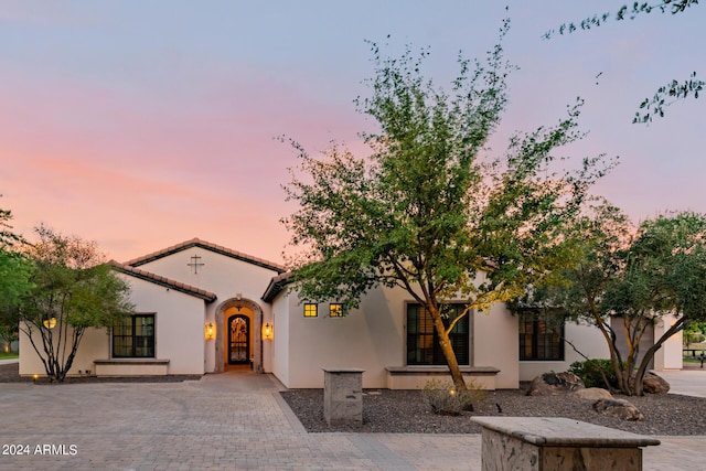 view of front facade featuring driveway, a tile roof, and stucco siding