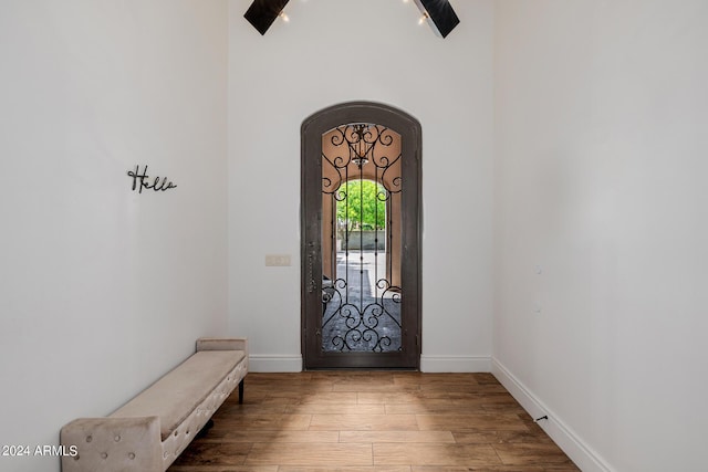 foyer featuring arched walkways, wood finished floors, and baseboards