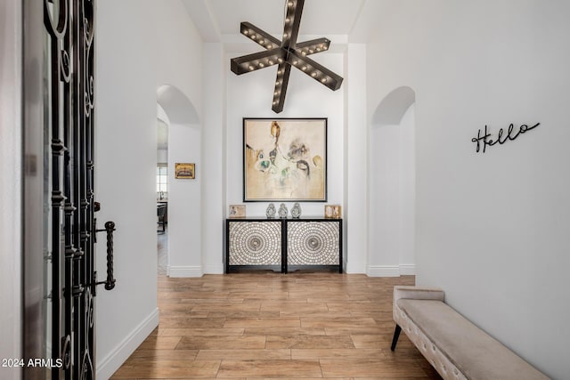 corridor with baseboards, arched walkways, and wood finished floors