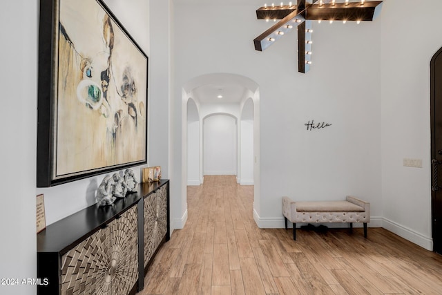 hallway featuring light wood-style floors, arched walkways, and baseboards