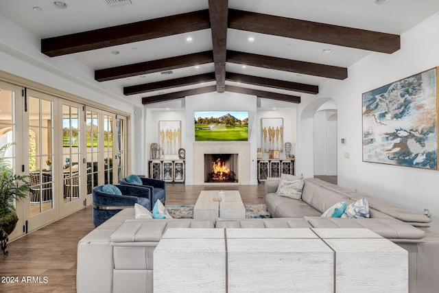 living room featuring arched walkways, french doors, vaulted ceiling with beams, a premium fireplace, and wood finished floors