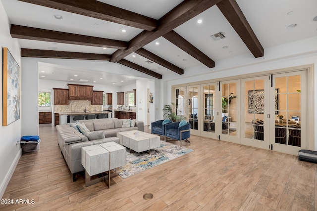 living room featuring baseboards, visible vents, lofted ceiling with beams, french doors, and light wood-style floors