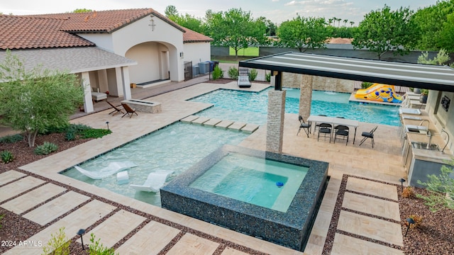 view of pool featuring pool water feature, cooling unit, an in ground hot tub, and a patio