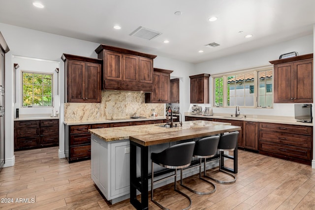 kitchen featuring light wood-style flooring, visible vents, decorative backsplash, and a sink