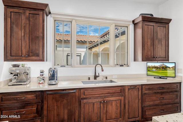 kitchen featuring light countertops, a sink, and dark brown cabinetry