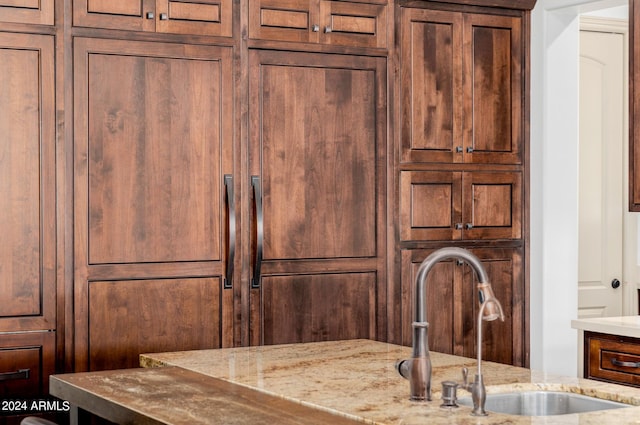 details featuring a sink and light stone countertops