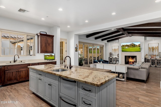 kitchen with light wood finished floors, visible vents, a sink, and a high end fireplace