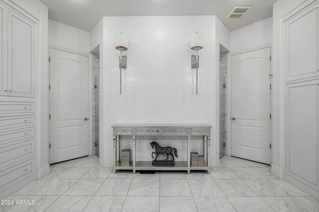 interior space with marble finish floor, visible vents, and a shower stall