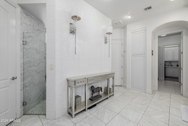 full bath with a stall shower, marble finish floor, visible vents, and a sink