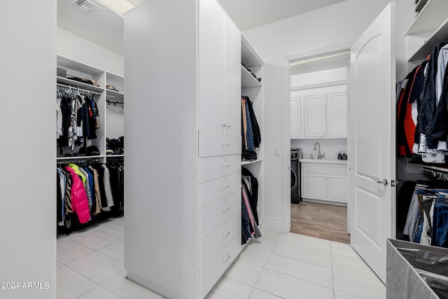 spacious closet with light tile patterned floors, visible vents, and a sink