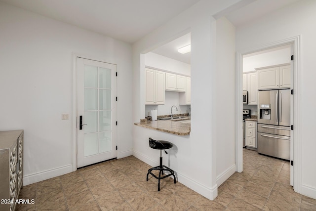 kitchen with white cabinetry, baseboards, stainless steel appliances, and a sink