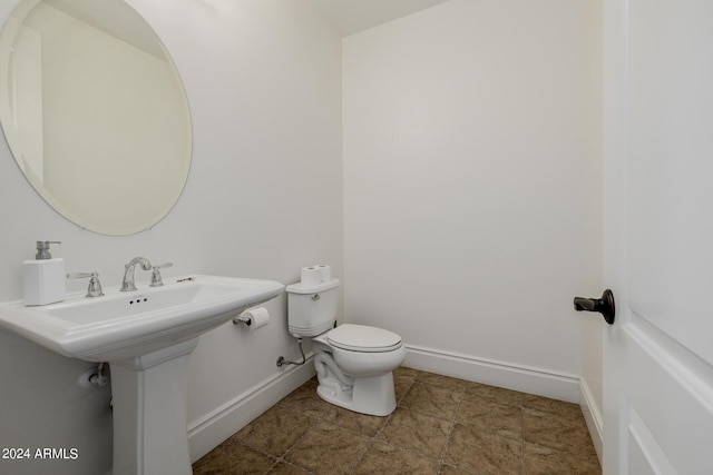 bathroom featuring toilet, baseboards, and a sink