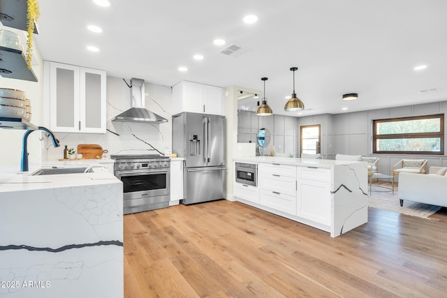 4910 E Shaw Butte Dr, Scottsdale, AZ 85254 - kitchen featuring appliances with stainless steel finishes, wall chimney exhaust hood, a peninsula, a sink, and light wood finished floors