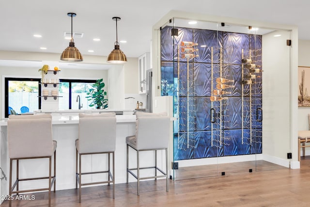 4910 E Shaw Butte Dr, Scottsdale, AZ 85254 - kitchen featuring a chandelier, recessed lighting, wood finished floors, a breakfast bar area, and hanging light fixtures