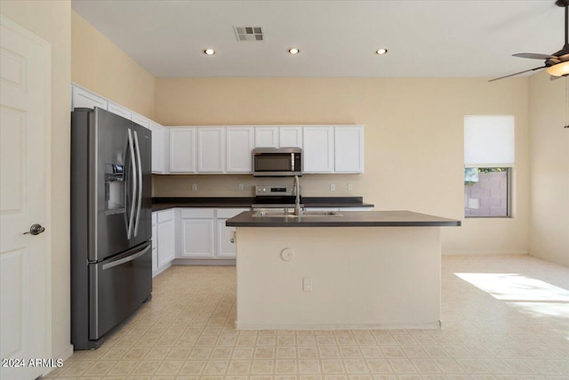 kitchen featuring stainless steel appliances, ceiling fan, sink, a center island with sink, and white cabinetry