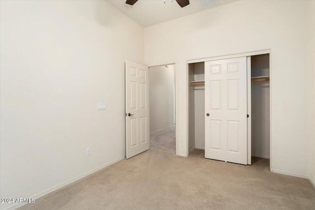 unfurnished bedroom with ceiling fan, light colored carpet, and a closet