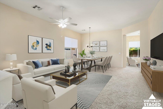 carpeted living room featuring ceiling fan with notable chandelier