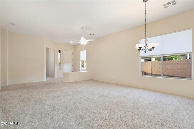 carpeted spare room with ceiling fan with notable chandelier