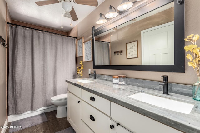 bathroom with a sink, toilet, double vanity, and wood finished floors