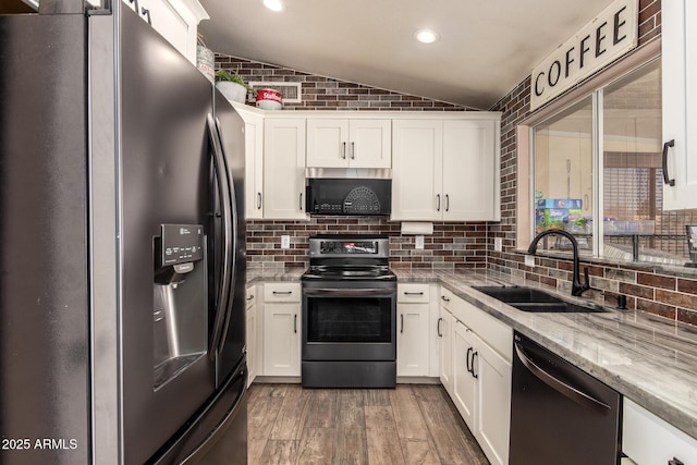 kitchen with wood finished floors, white cabinetry, a sink, vaulted ceiling, and stainless steel appliances