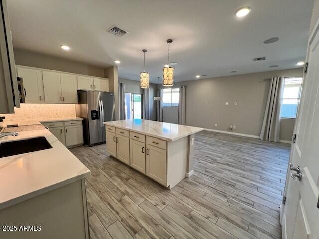 17066 W Seldon Ln, Waddell, AZ 85355 - kitchen with stainless steel refrigerator with ice dispenser, a sink, light countertops, light wood finished floors, and recessed lighting