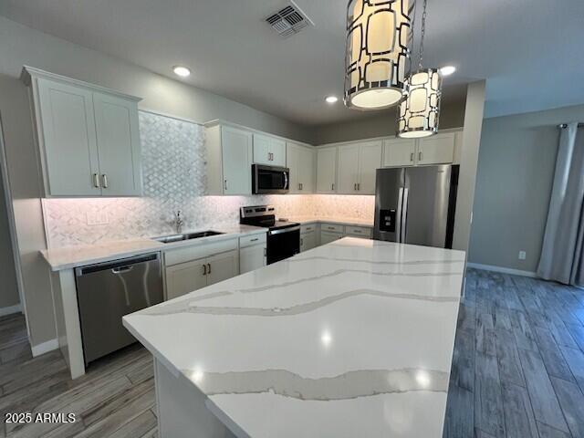 17066 W Seldon Ln, Waddell, AZ 85355 - kitchen featuring appliances with stainless steel finishes, a sink, a center island, light wood-style floors, and recessed lighting