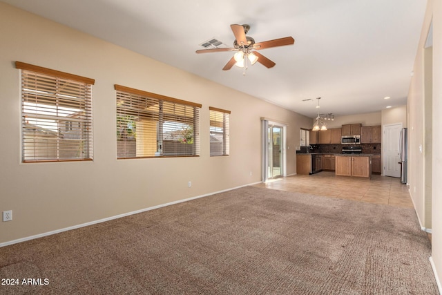 unfurnished living room with light carpet, sink, and ceiling fan with notable chandelier