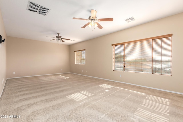 spare room with ceiling fan, plenty of natural light, and light colored carpet