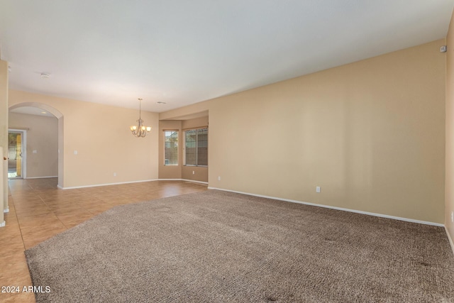 tiled spare room featuring an inviting chandelier