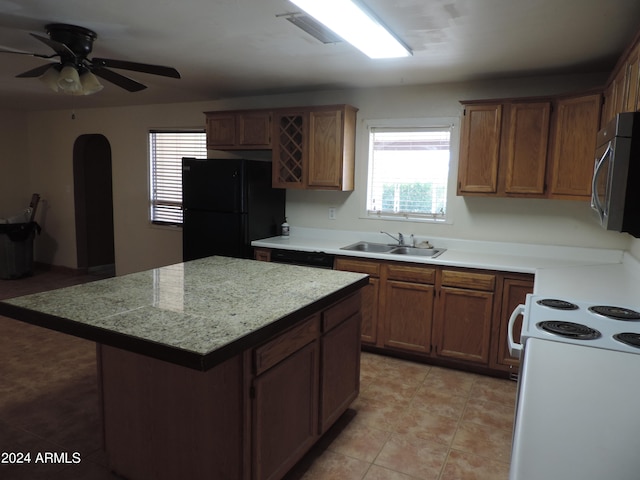 kitchen with a kitchen island, black refrigerator, sink, electric range, and ceiling fan