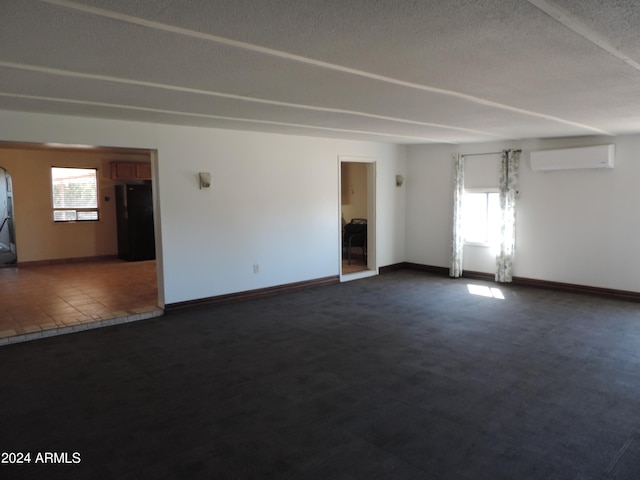 carpeted empty room featuring a textured ceiling, a wall mounted AC, and a wealth of natural light