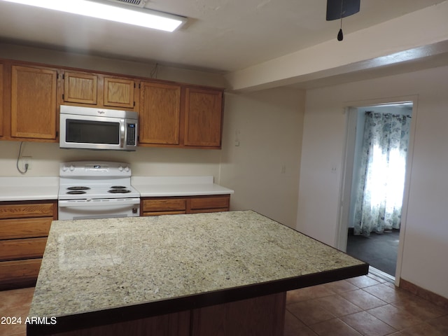 kitchen featuring white electric range, a center island, and dark tile patterned floors