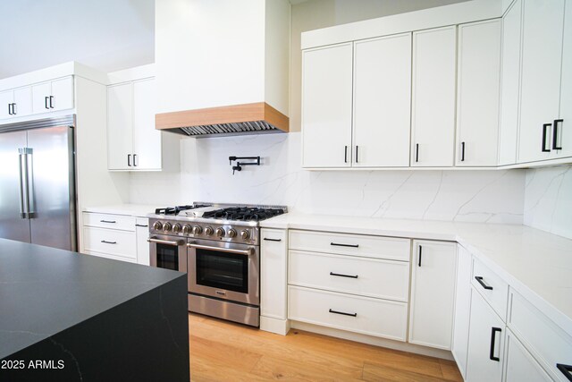 7724 E Charter Oak Rd, Scottsdale, AZ 85260 - kitchen featuring premium appliances, custom exhaust hood, decorative backsplash, and white cabinetry