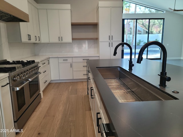 7724 E Charter Oak Rd, Scottsdale, AZ 85260 - kitchen featuring range with two ovens, wall chimney range hood, light wood-style flooring, open shelves, and tasteful backsplash