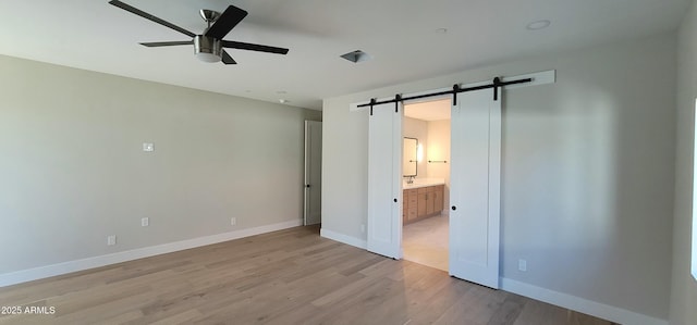 7724 E Charter Oak Rd, Scottsdale, AZ 85260 - unfurnished bedroom with a barn door, light wood finished floors, ensuite bathroom, and a ceiling fan