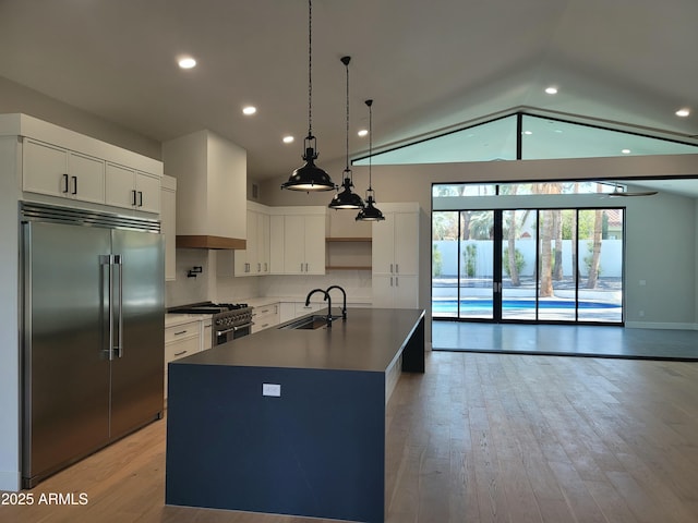 7724 E Charter Oak Rd, Scottsdale, AZ 85260 - kitchen featuring premium appliances, vaulted ceiling, backsplash, light wood-type flooring, and an island with sink