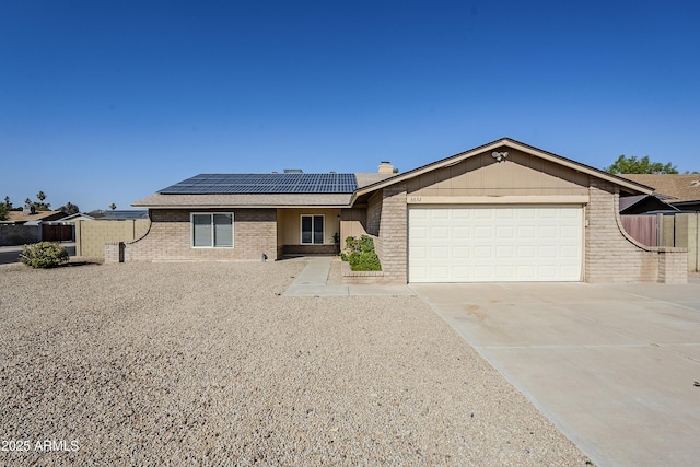 ranch-style house with a garage and solar panels