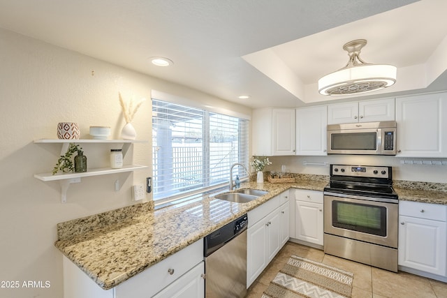 kitchen with pendant lighting, sink, appliances with stainless steel finishes, white cabinetry, and light stone countertops