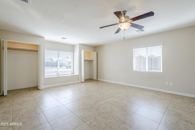 unfurnished bedroom featuring multiple closets, ceiling fan, and light tile patterned floors