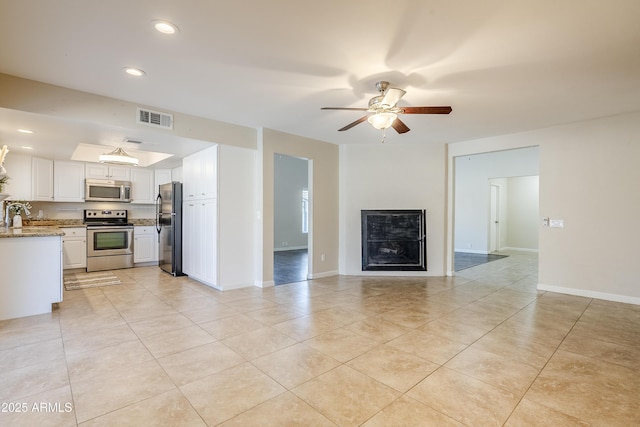 unfurnished living room featuring ceiling fan, sink, and light tile patterned floors