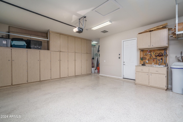 garage with a workshop area, a garage door opener, and sink