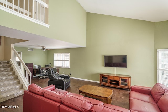 living area with baseboards, a high ceiling, visible vents, and a ceiling fan