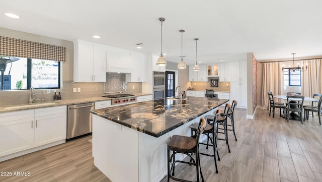 5971 E Orange Blossom Ln, Phoenix, AZ 85018 - kitchen with stainless steel appliances, backsplash, light wood finished floors, a chandelier, and white cabinetry