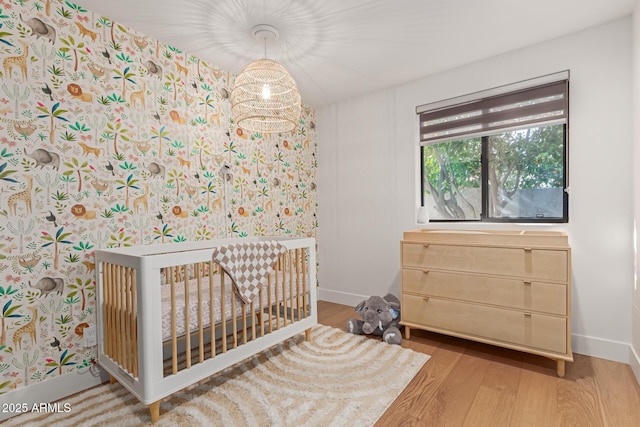 bedroom featuring a nursery area and wood-type flooring