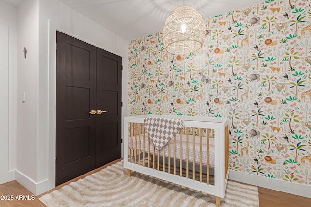 bedroom with hardwood / wood-style flooring and a crib