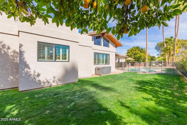 back of property with a fenced in pool and a lawn