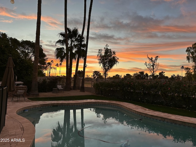 pool at dusk with a patio area