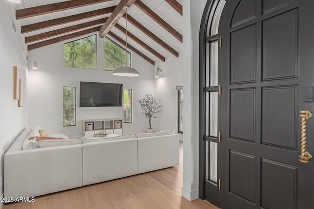 living room featuring beamed ceiling, high vaulted ceiling, a healthy amount of sunlight, and light wood-type flooring