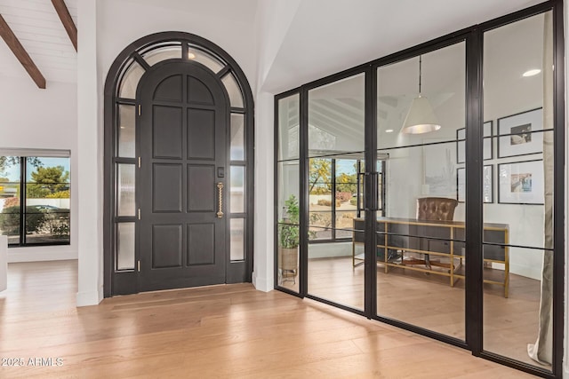 entrance foyer featuring lofted ceiling with beams and light hardwood / wood-style floors