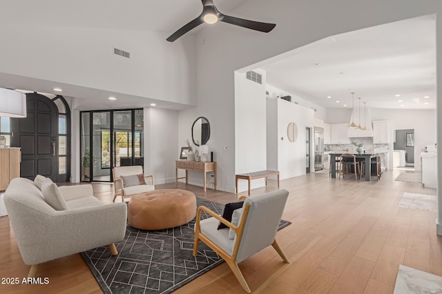 living room with ceiling fan, high vaulted ceiling, and light wood-type flooring